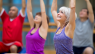 Group Pilates Class showing people sitting and stretching their arms over their heads